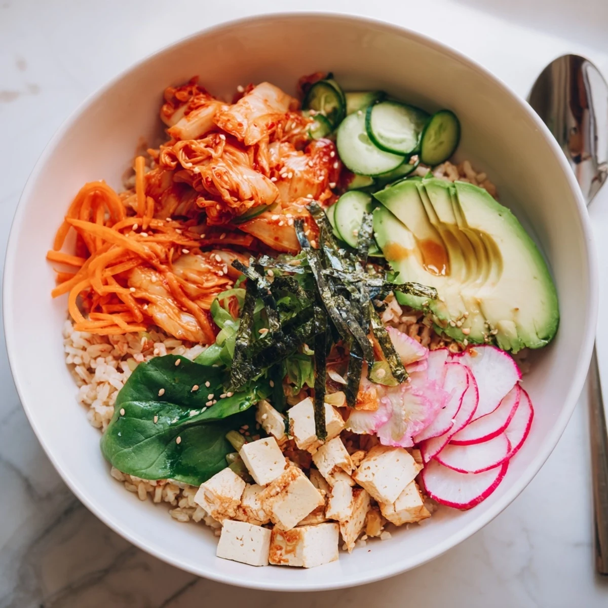 A colorful fermented vegetable bowl with kimchi, fresh greens, and avocado slices.  