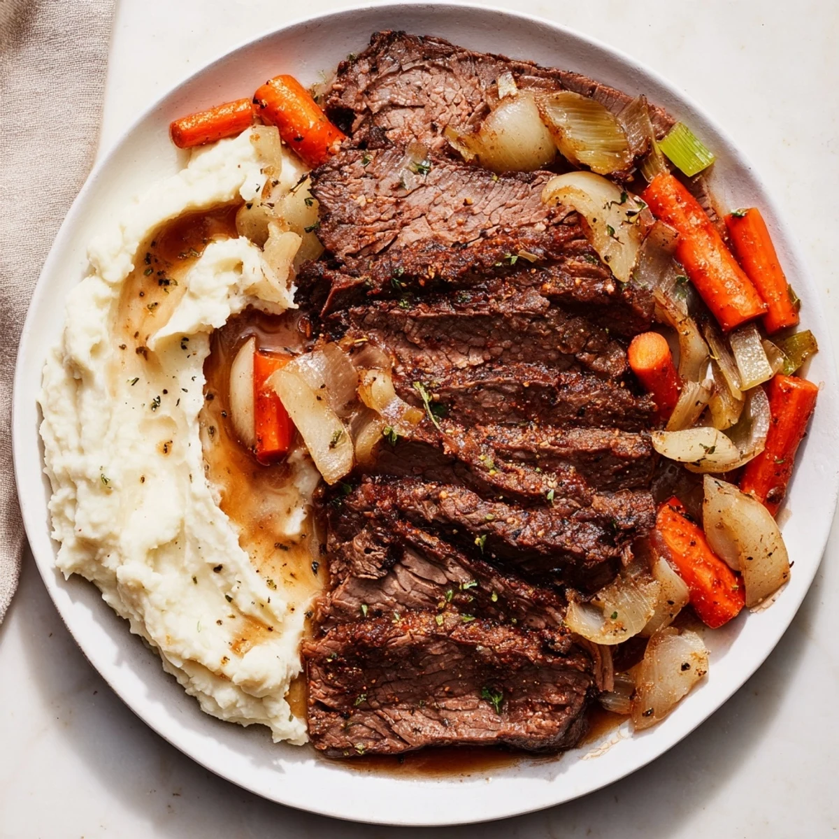 Tender classic brisket cut across the grain, served beside creamy mashed sweet potatoes, a satisfying dinner.