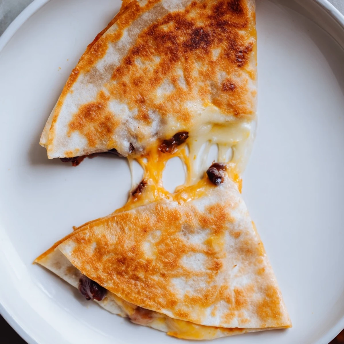 Crispy-edged Bean & Cheese Quesadillas, folded tortillas overflowing with beans and bubbling, golden cheese, ready to eat.