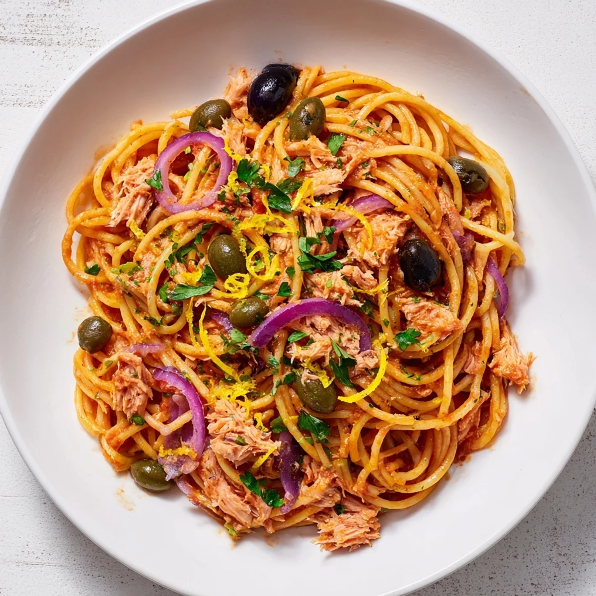 This pasta with tuna, olives, and capers boasts a vibrant tomato sauce and flaky tuna chunks awaiting.