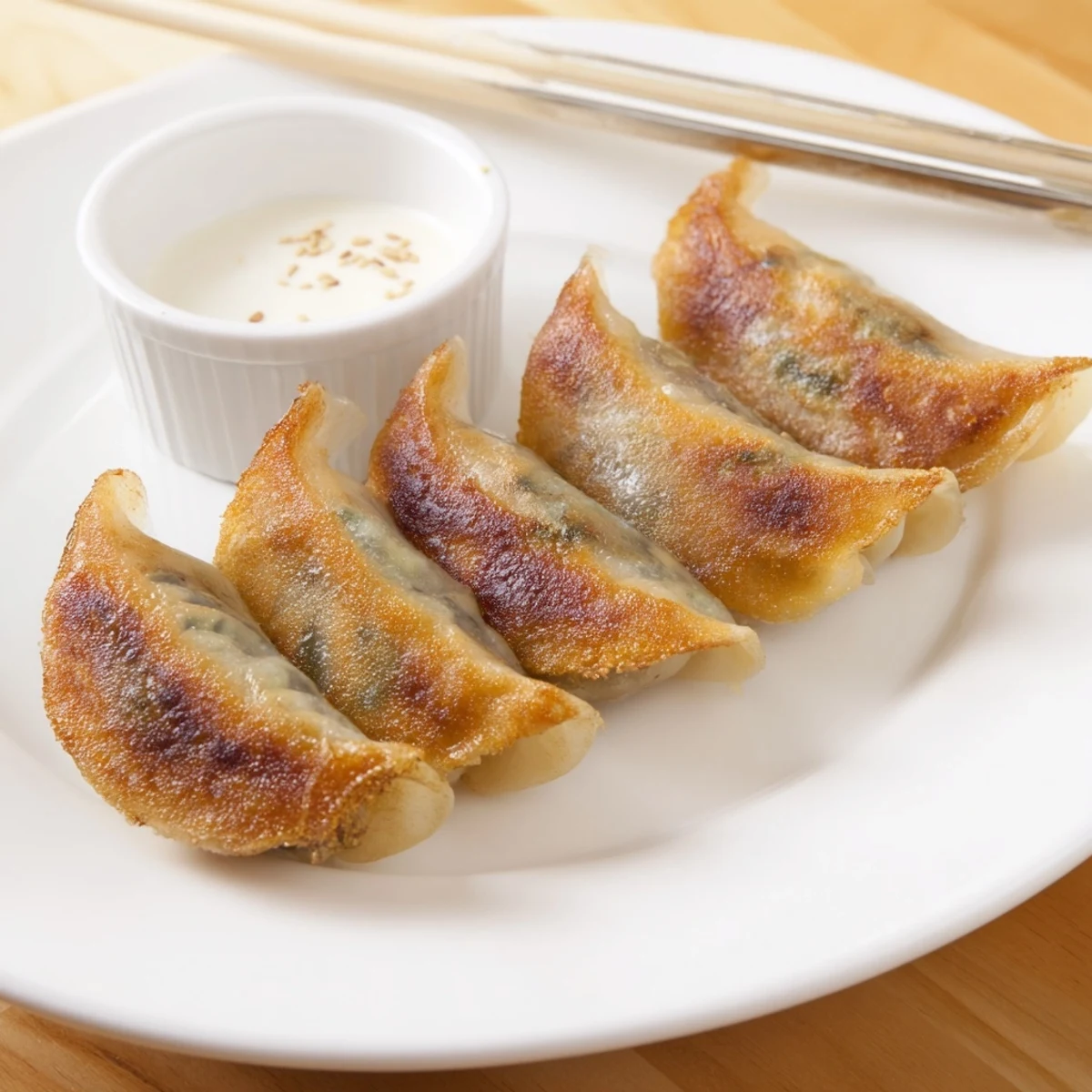 Golden-brown smashed gyozas sizzling in a skillet, topped with sliced green onions and a small bowl of dipping sauce.