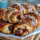 Mini pigs in a blanket with dipping sauce, golden pastry-wrapped sausages on a party platter.  