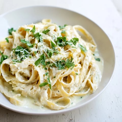 Steaming bowl of Skinny Alfredo Garlic Parmesan Snowy Pasta, a lighter creamy pasta dish, ready to eat.