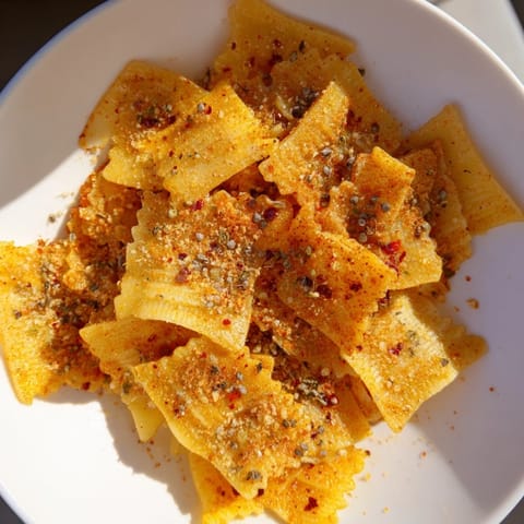 Golden-baked pasta chips seasoned with garlic and paprika, ideal for snack lovers.  