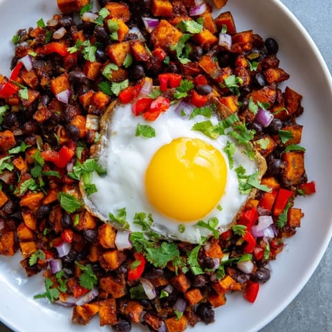 Hearty Sweet Potato & Black Bean Breakfast Hash piled high in a skillet, with colorful peppers and cilantro.