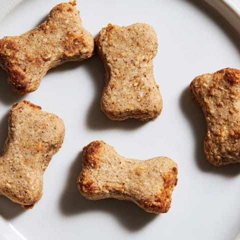 A batch of homemade Pawsitively Good Dog Bone Treats, carefully cut into bone shapes, waiting to be baked.