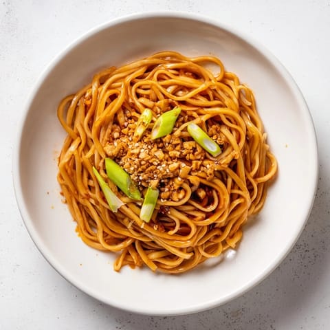 Mouthwatering, close-up shot of perfectly cooked Garlic Chili Oil Noodles with sesame seeds.