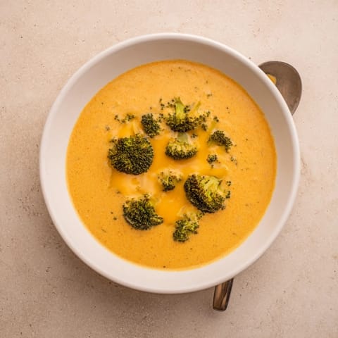 Steaming Broccoli Cheddar Soup is ladled into a rustic bread bowl, offering a comforting meal for cold evenings.