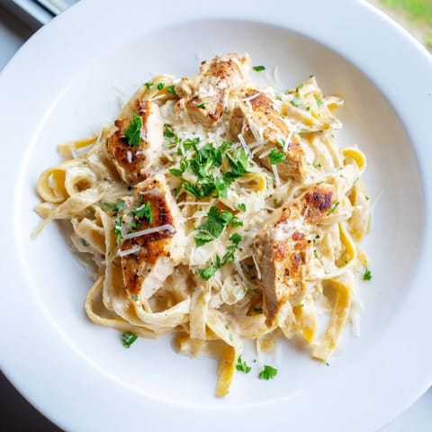 Golden Skillet Chicken Alfredo with tender strips of chicken nestled in creamy, cheesy sauce over perfectly al dente fettuccine, garnished with fresh parsley and extra Parmesan for a comforting Italian-American weeknight dinner.  