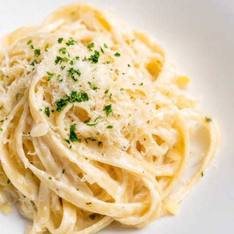 Golden roasted garlic cloves enrich this vegetarian pasta dish, garnished with parsley for a fresh finish.  