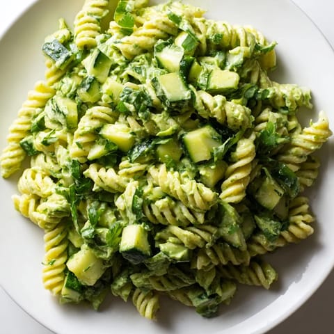 Green Goddess Pasta Salad with creamy avocado-yogurt dressing, tender pasta, crisp cucumbers, and fresh herbs, served in a white bowl.