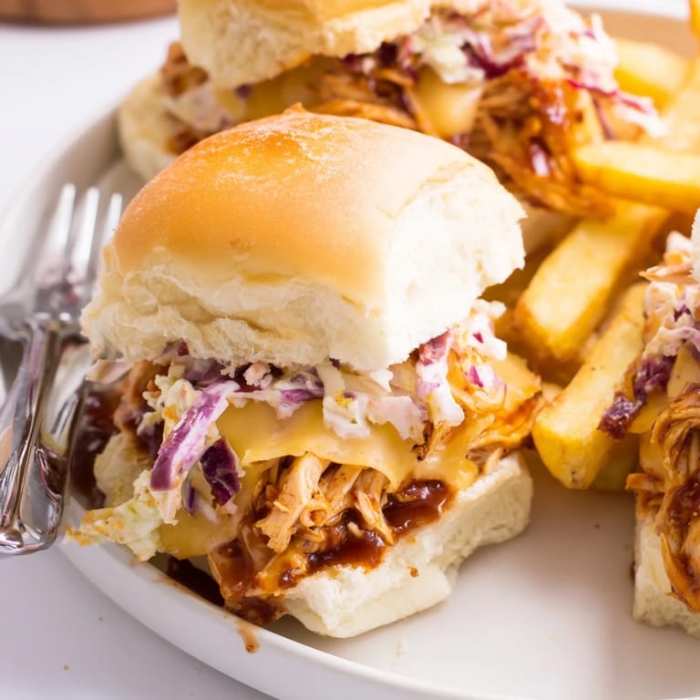 Tender shredded BBQ chicken sliders topped with cheddar and fresh coleslaw for flavor.  