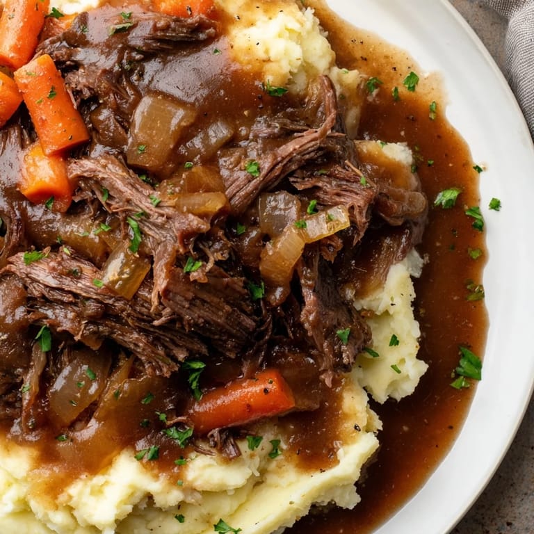 A flavorful serving of Slow Cooker Pot Roast, featuring juicy beef, aromatic vegetables, and creamy mashed potatoes.