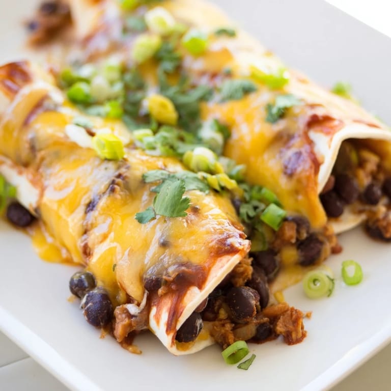 Melted cheese blankets these flavorful cheesy bean enchiladas, a perfectly baked Mexican comfort food.