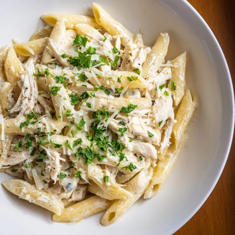 Close-up of Tinis Creamy Chicken Pasta, showing perfect penne coated with creamy sauce and herbs.