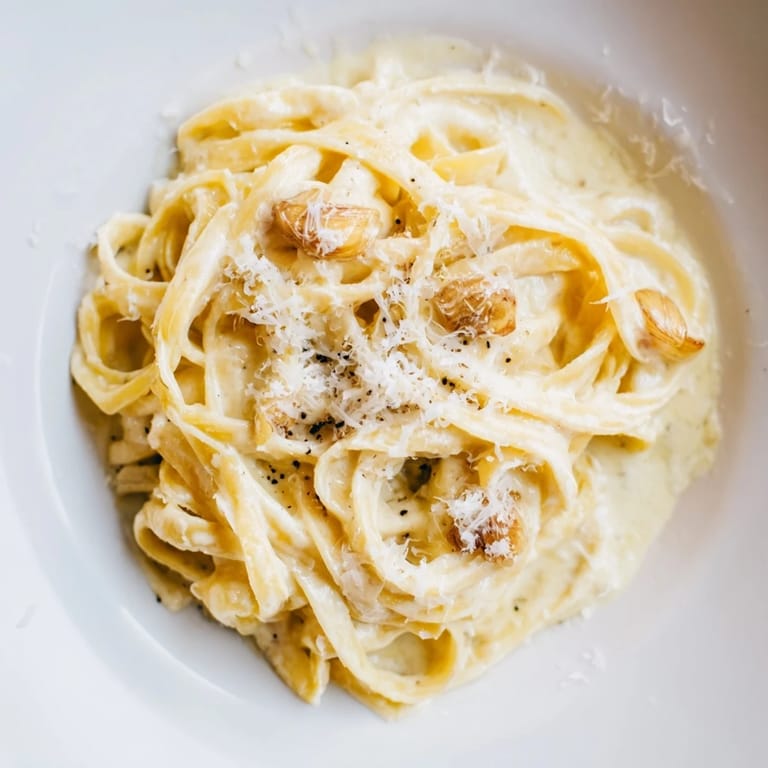 A comforting bowl of roasted garlic cream pasta, steam rising from the freshly tossed, cheesy noodles.